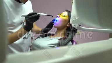 戴着黄色防护眼镜的年轻女子在牙科医生办公室用<strong>紫外线</strong>`机器进行<strong>紫外线</strong>美白